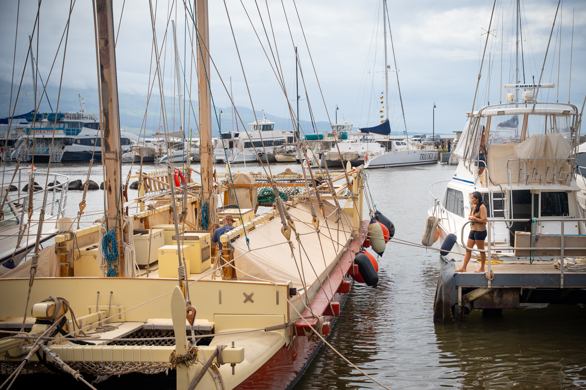 A woman faces a large canoe in Māʻalaea harbor. 
